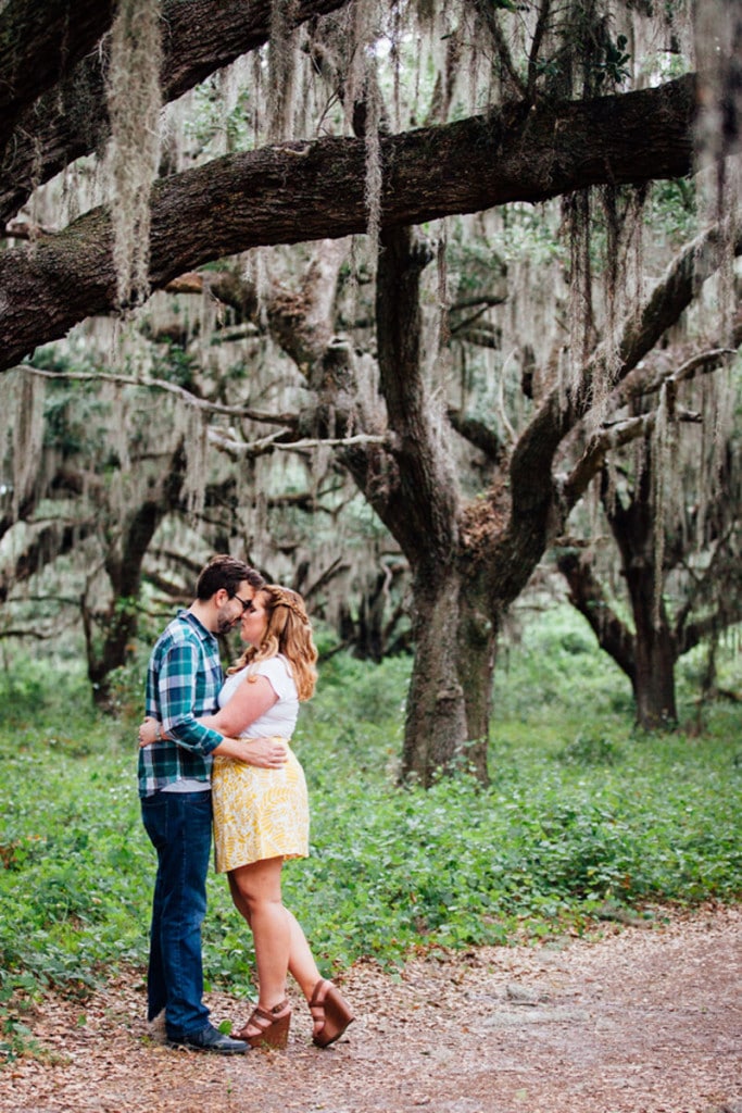 couple standing under large oak trees