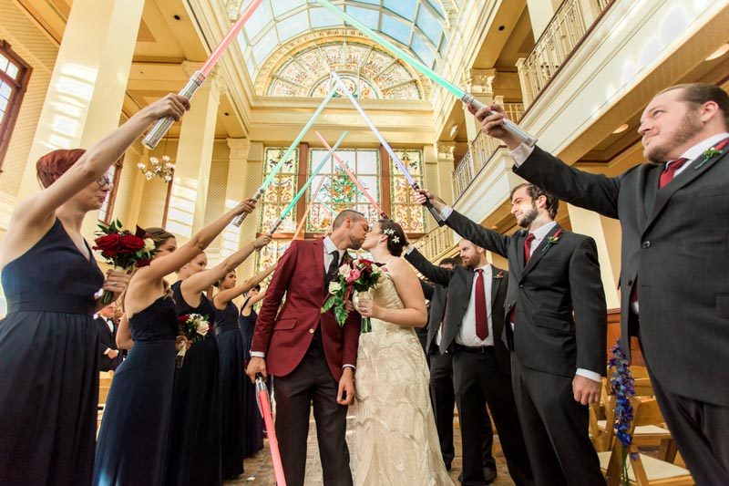 bride and groom standing under lightsaber tunnel