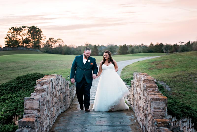 Bride and groom walking over stone bridge at The Royal Crest Room in Saint Cloud FL