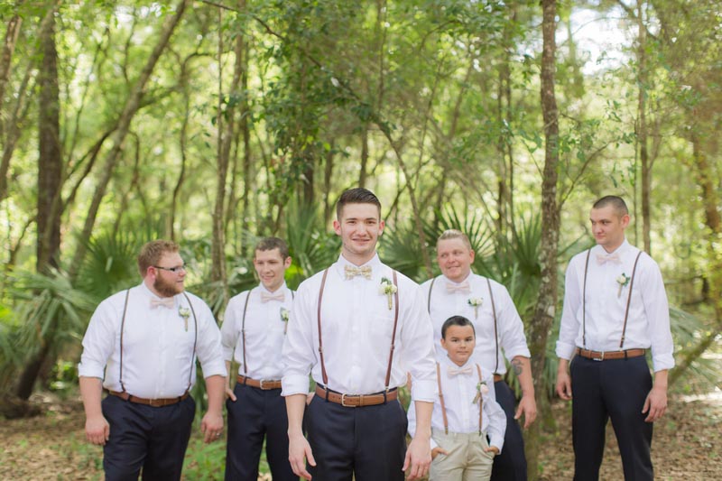 groom and groomsmen in navy pants and brown suspenders