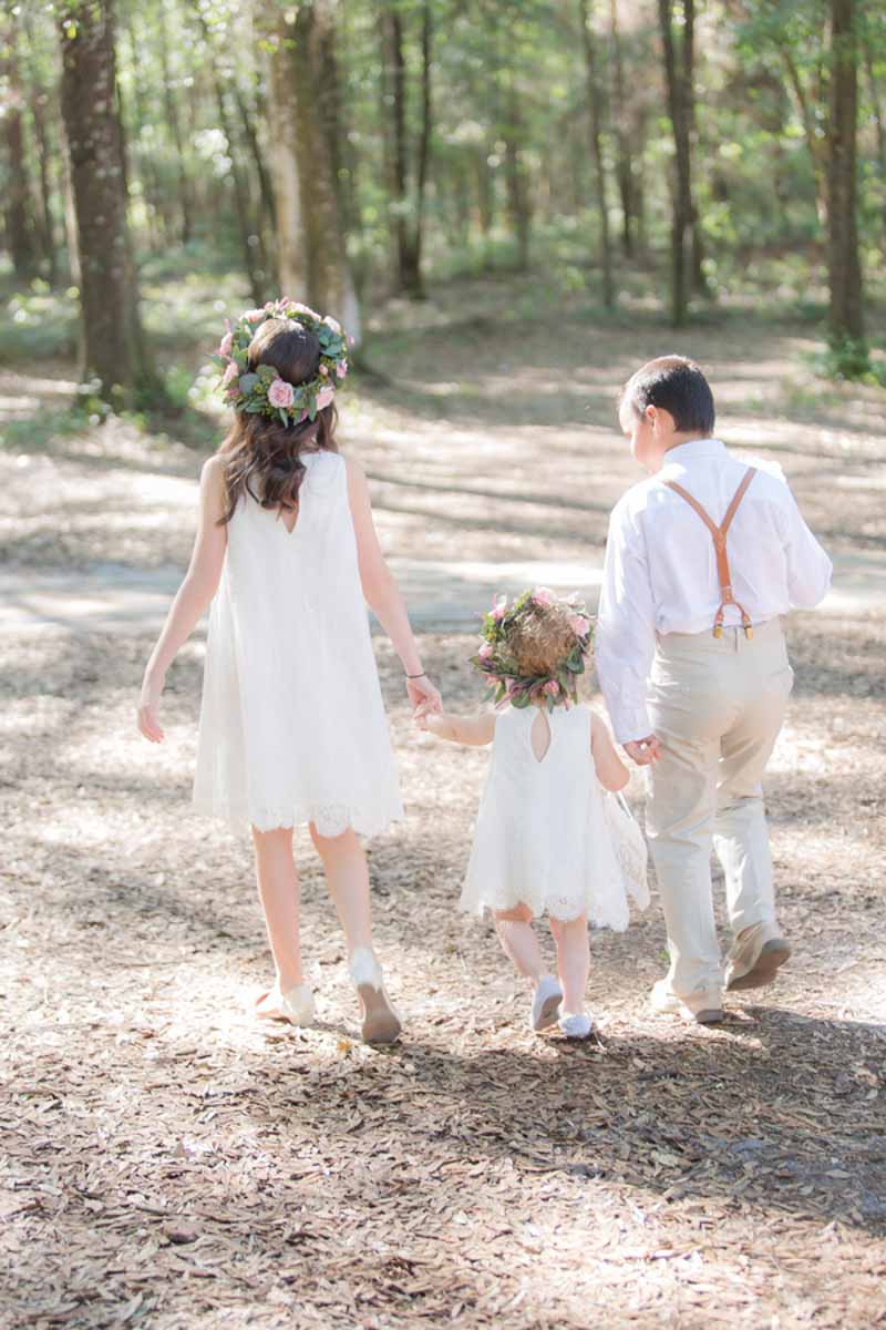 flower girl, junior bridesmaid, and ring bearer walking in woods