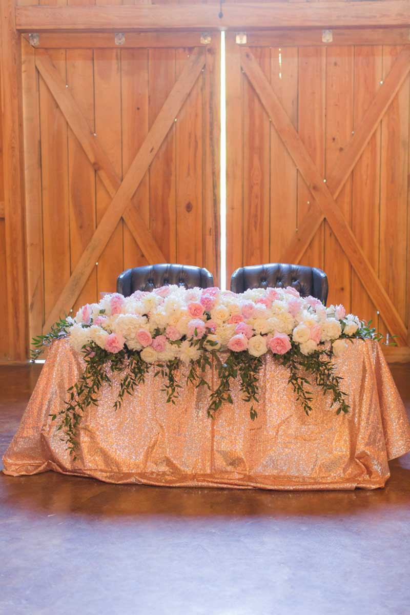 sweetheart table with large floral blush and white peonies in barn