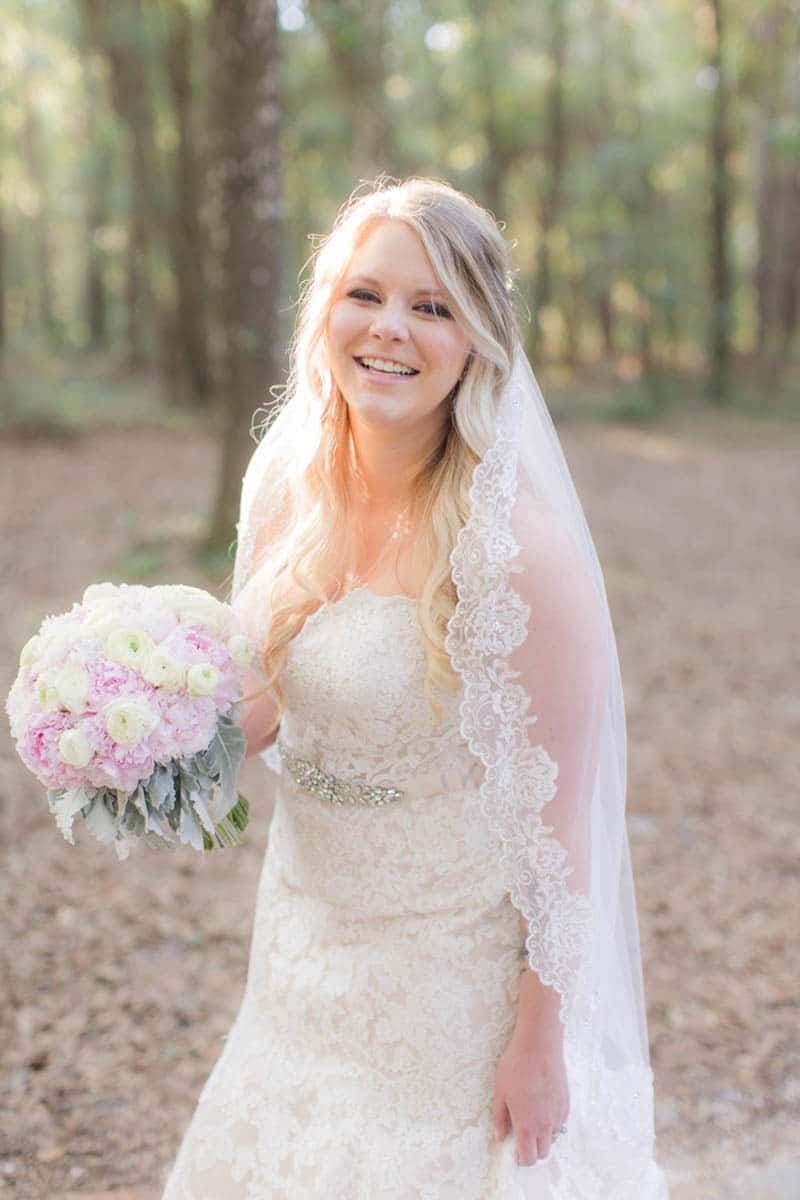 bride smiling at camera and holding blush peony bridal bouquet