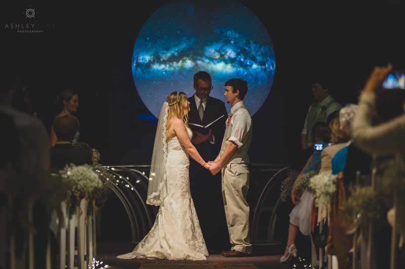 couple standing in front of planet for wedding ceremony at the Orlando Science Center