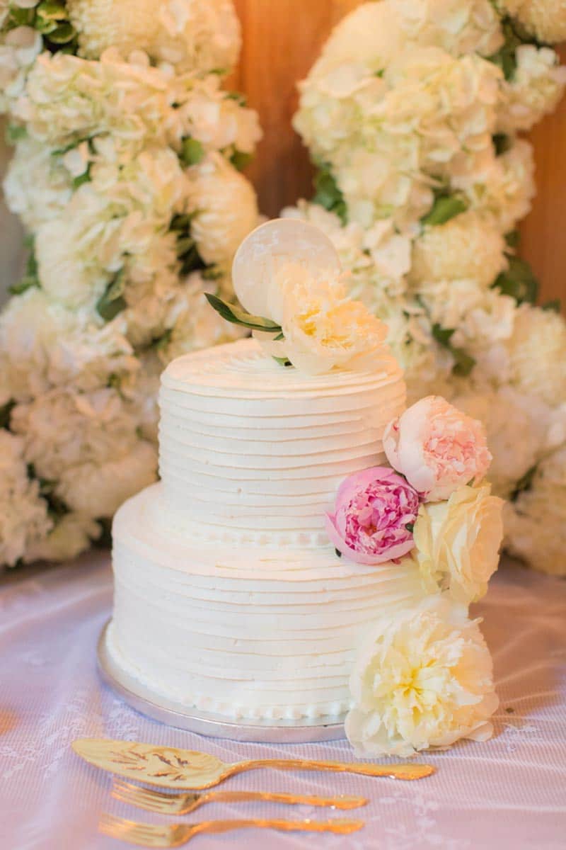 two tier white buttercream cake with blush peonies flowers
