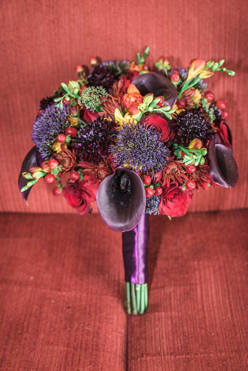 red and purple bridal bouquet on red couch