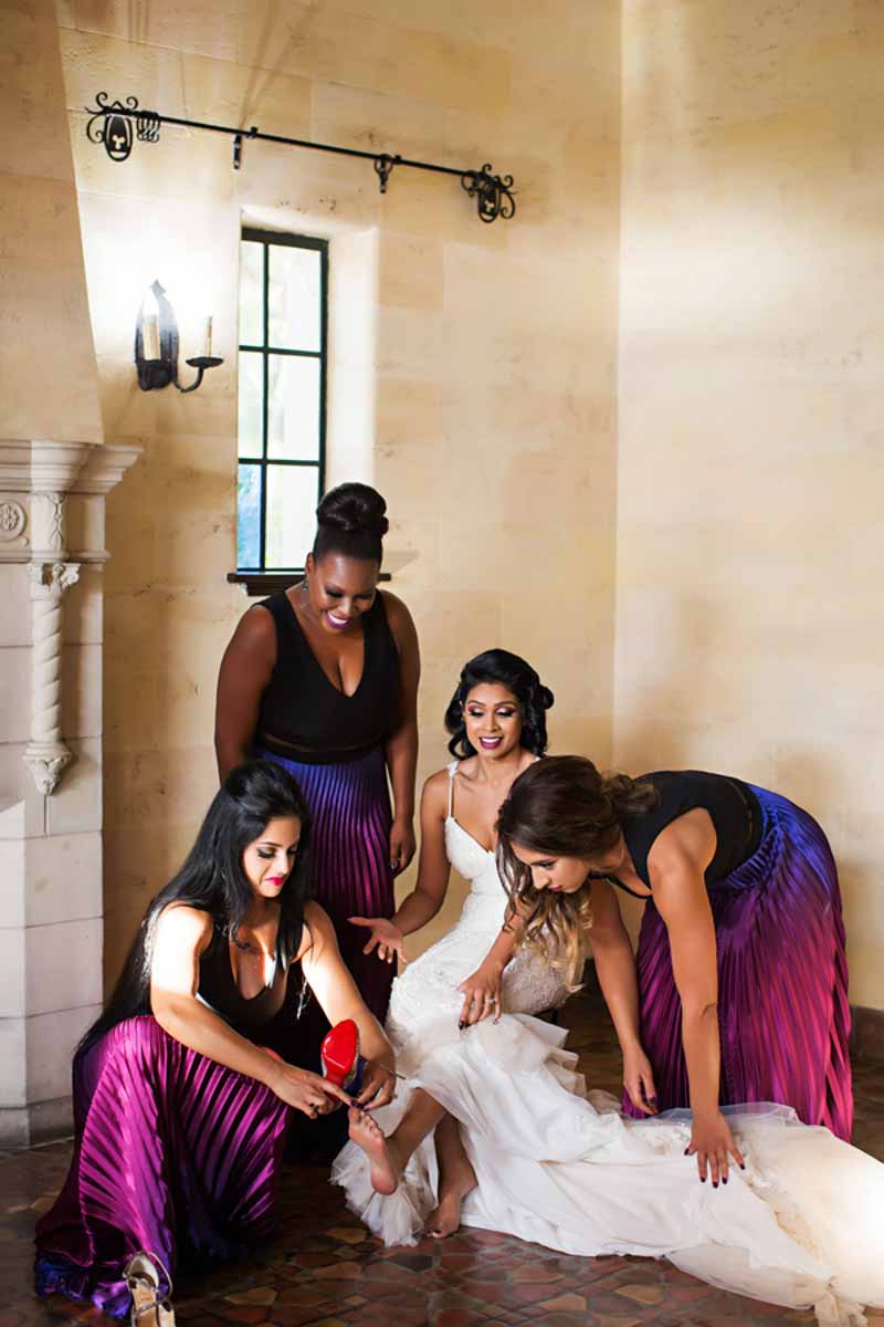 bridesmaids helping bride put shoes on