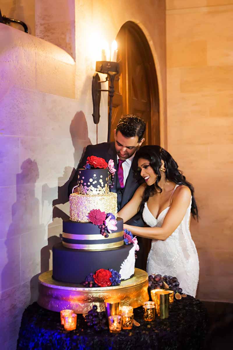 couple cutting black and gold wedding cake