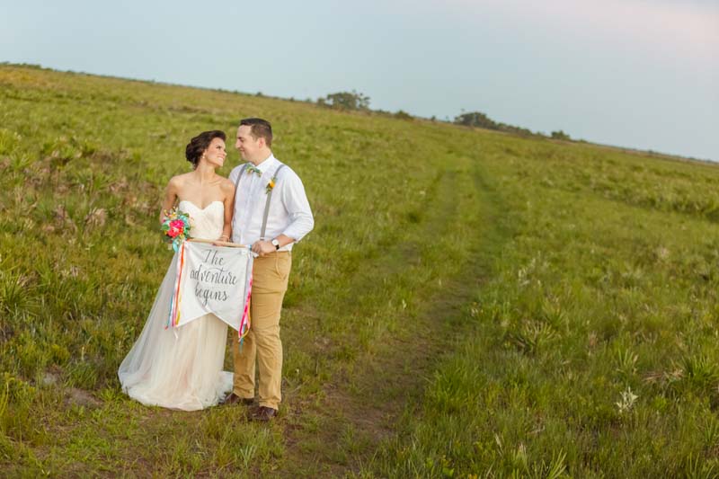 couple holding the adventure begins sign