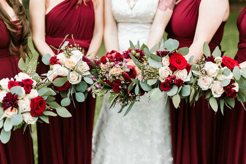 bride and bridesmaids holding burgundy and blush bouquets