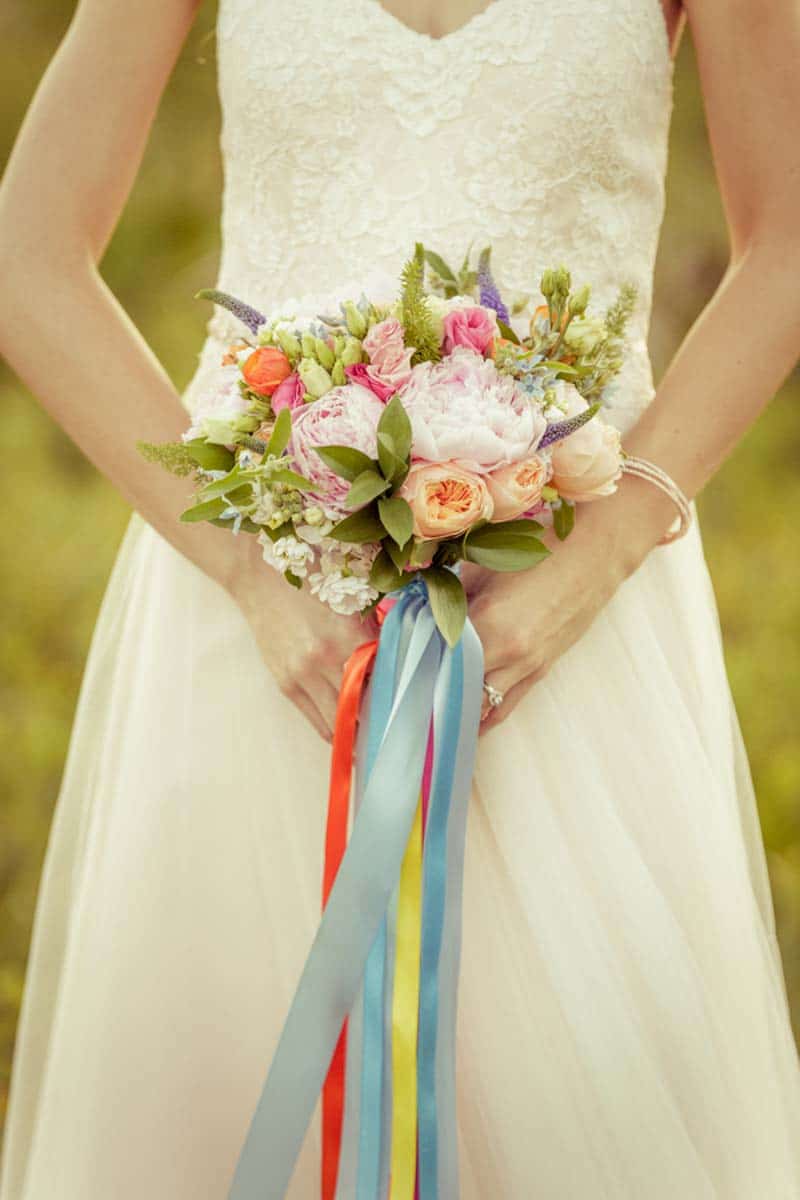 bride holding blush and orange bridal bouquet