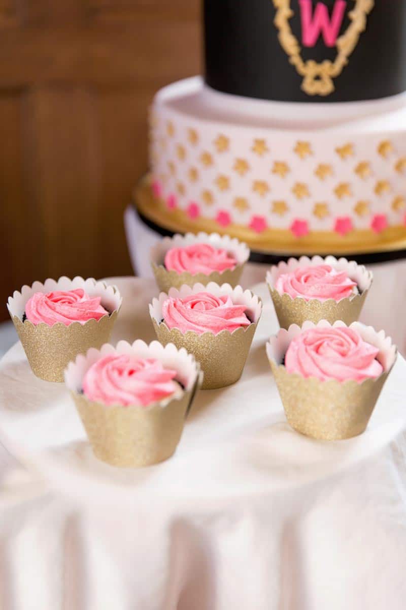 pink frosting cupcakes next to wedding cake
