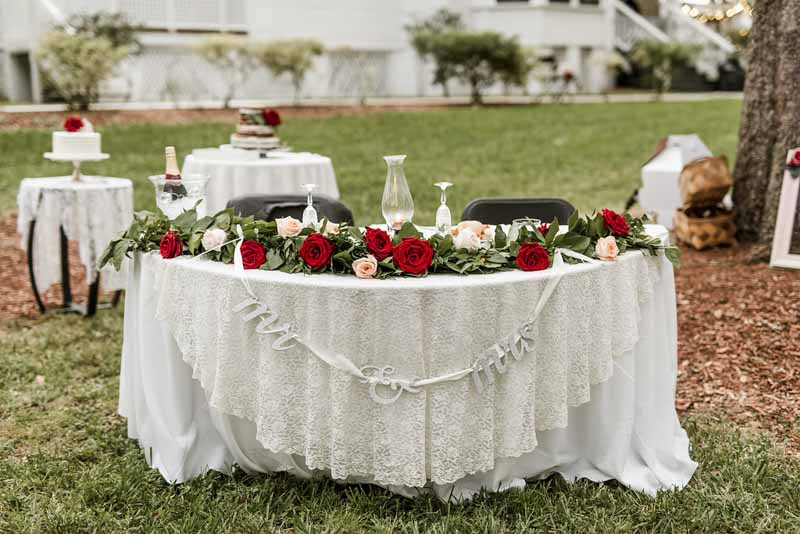 sweetheart table with red rose garland across