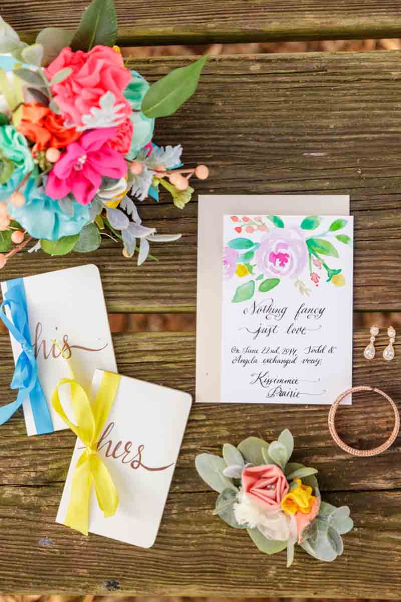 watercolor invitation and vow books on wood table