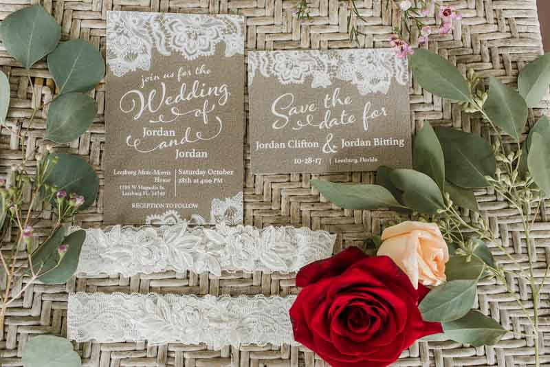 taupe wedding invitations on basket next to lace garter