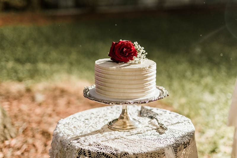 white buttercream wedding cake with red rose on top