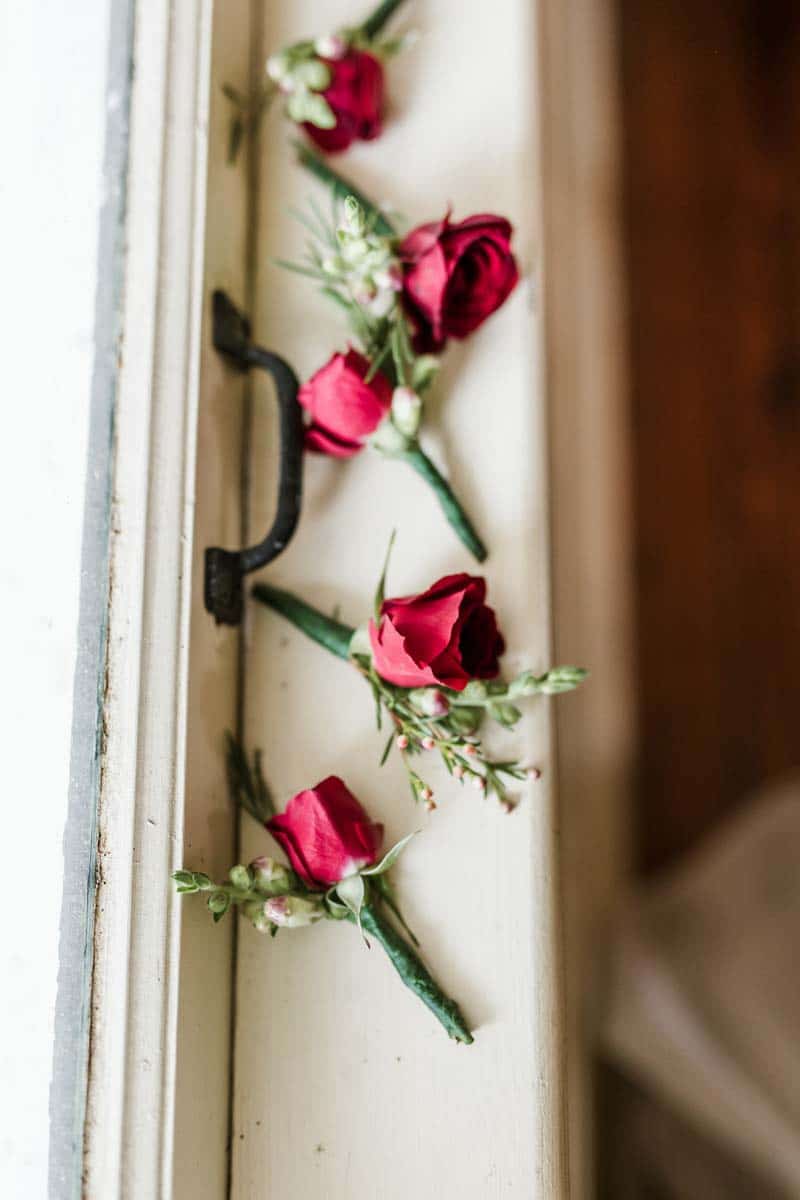 red rose bountonierres on window sill