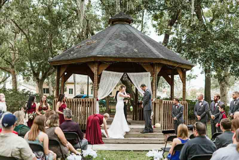 bride and groom standing in front of gazebo for wedding ceremony