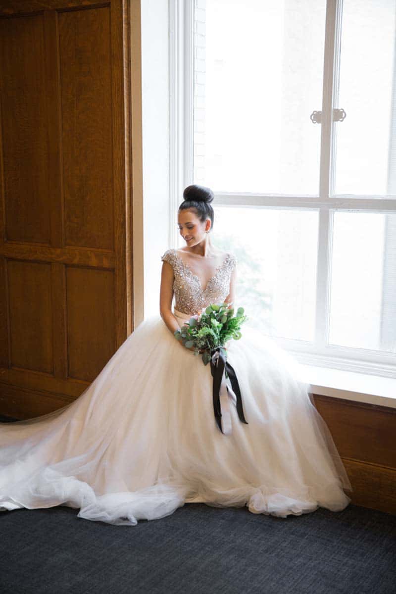 bride sitting on window sill holding bouquet