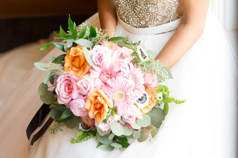 bride holding pink and orange bouquet