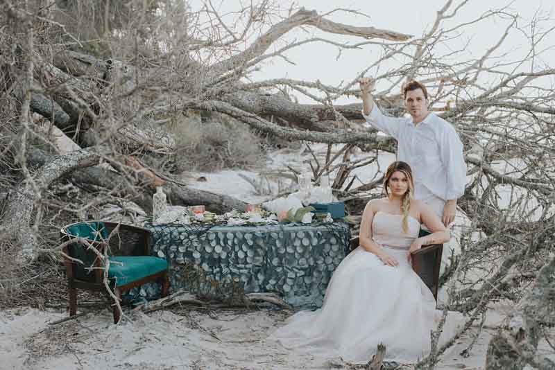 bride and groom next to sweetheart table on the beach