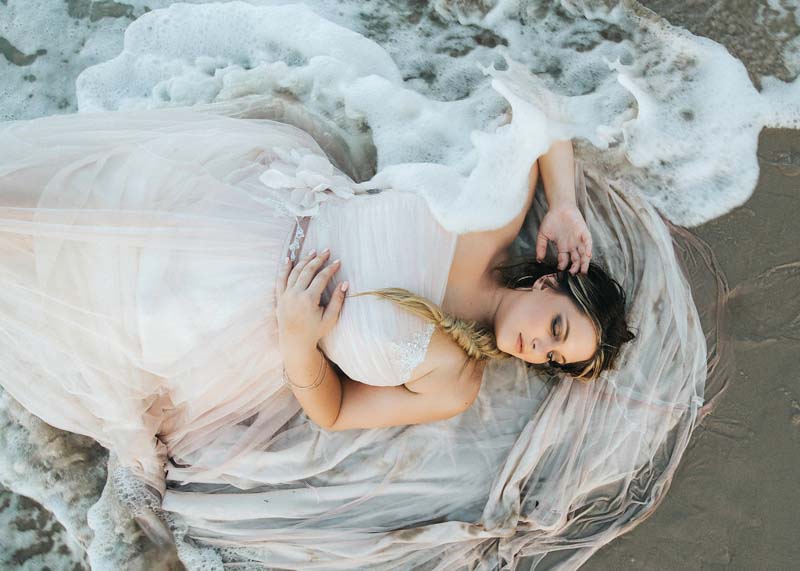 bride laying on shoreline with waves