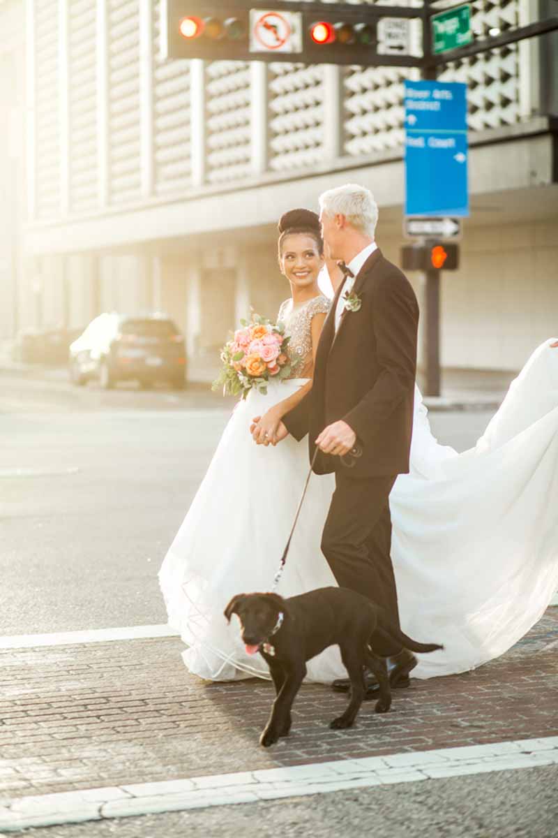 bride and groom walking puppy across street