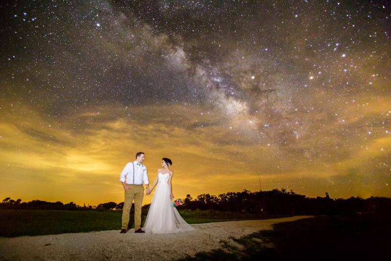 bride and groom holding hands under the milky way