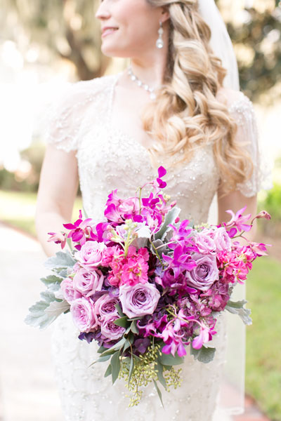 bride looking over shoulder holding lavender rose bouquet