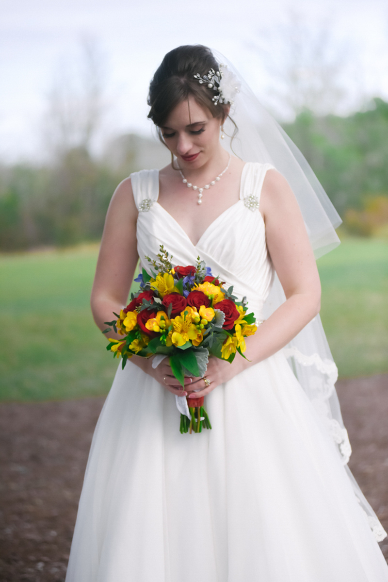 bride looking down at yellow and red bouquet
