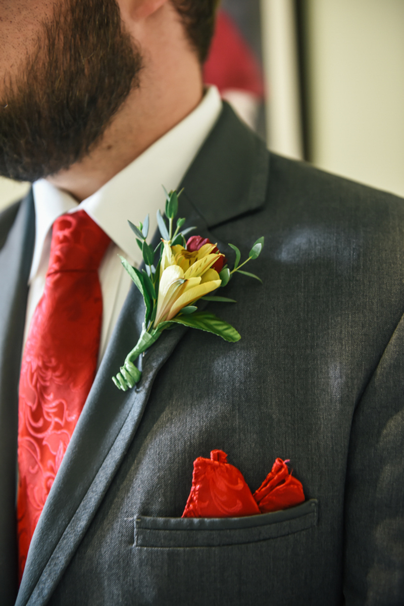yellow and red boutonniere on grey suit