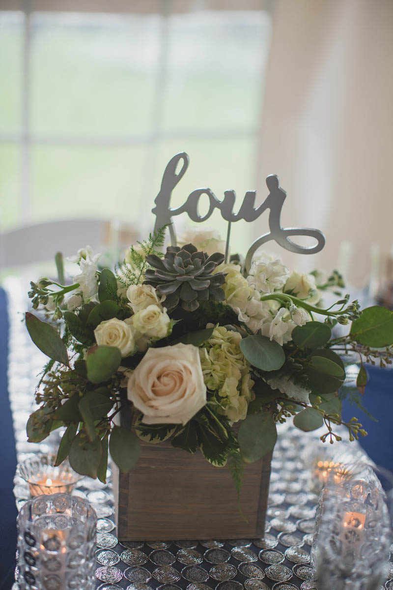 white wedding centerpiece with silver "four" table number in it.