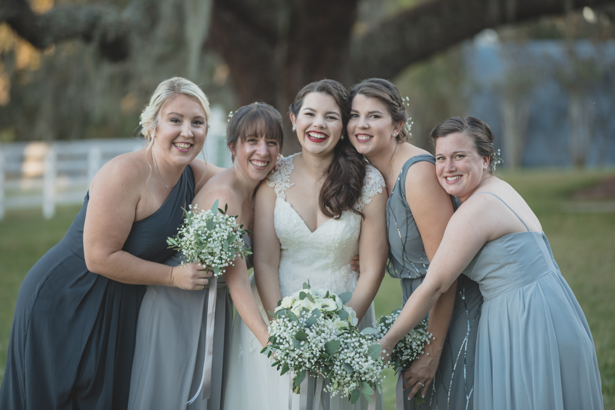 bridesmaids in grey dresses hugging bride for Highland Manor wedding