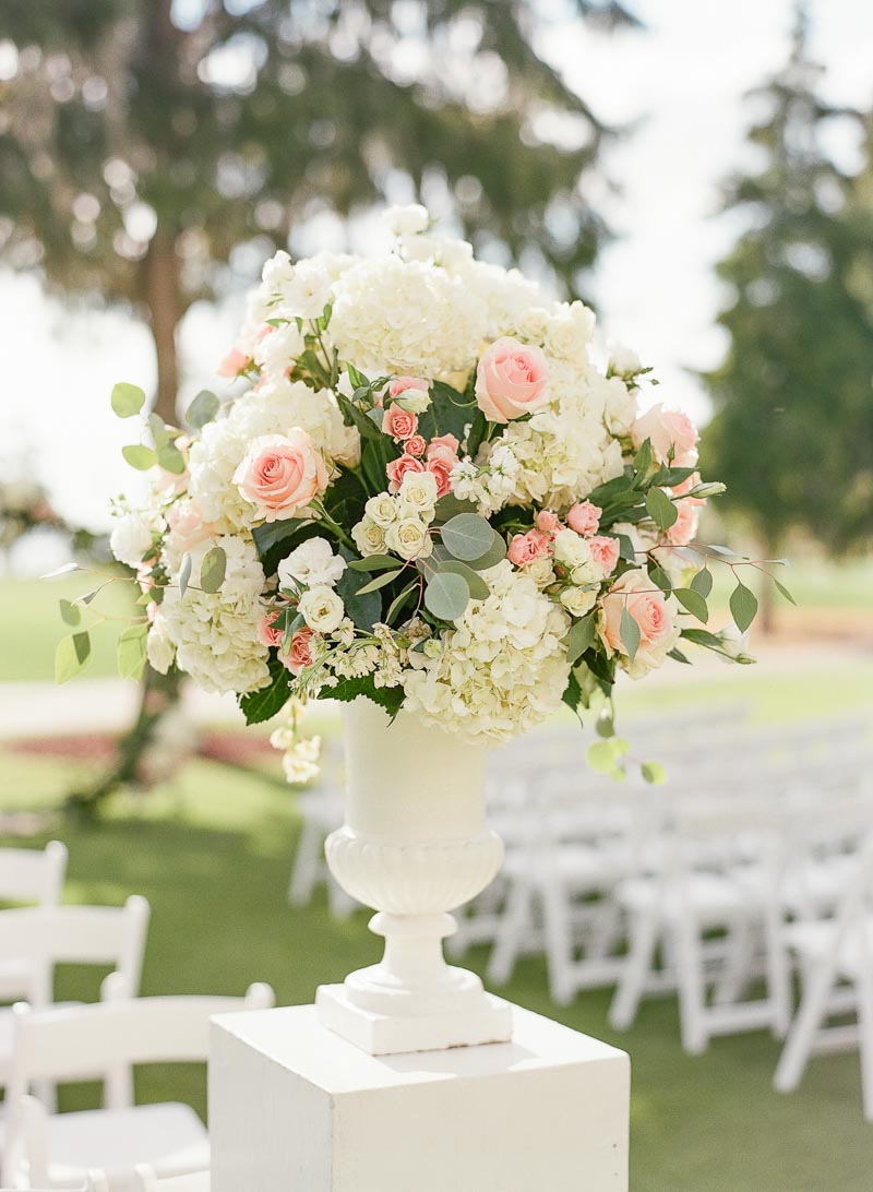 white and blush wedding ceremony flower arrangement on stand 