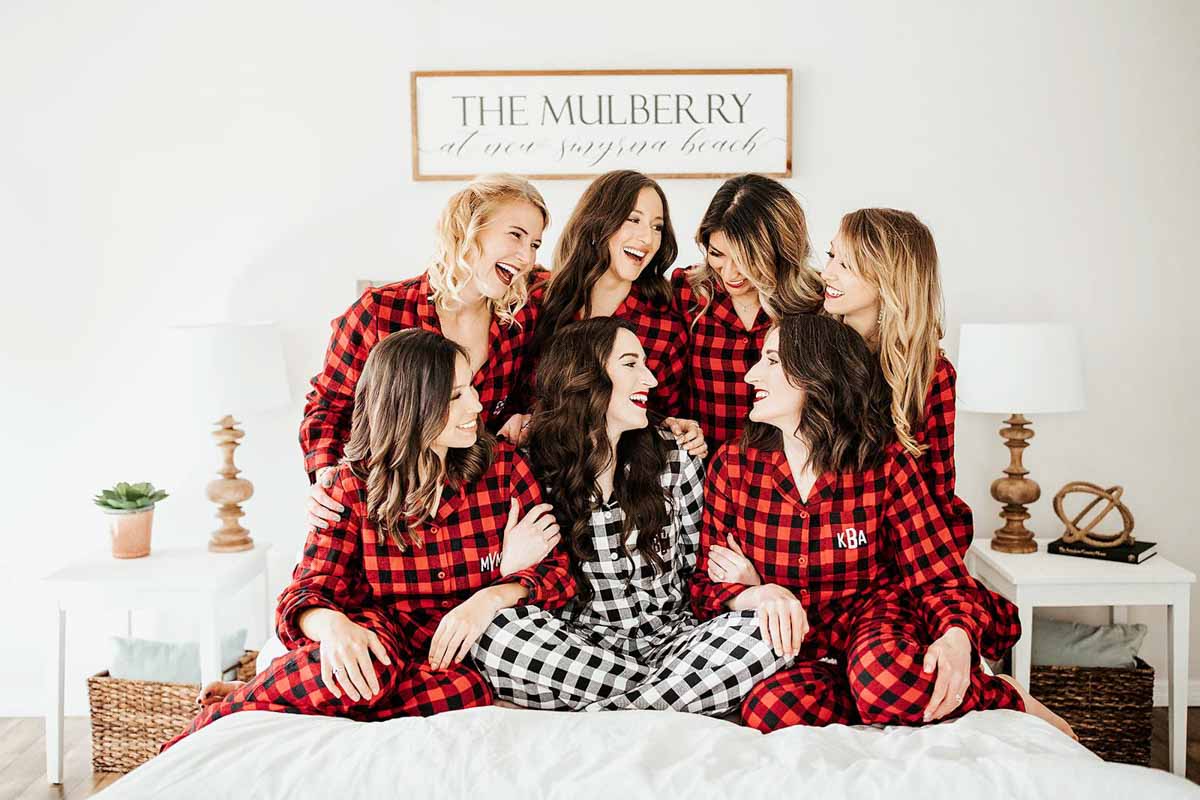 bride and bridesmaids in plaid on bed getting ready for wedding at The Mulberry