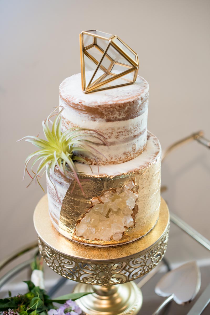 semi naked geode style wedding cake on gold stand with metal diamond on top