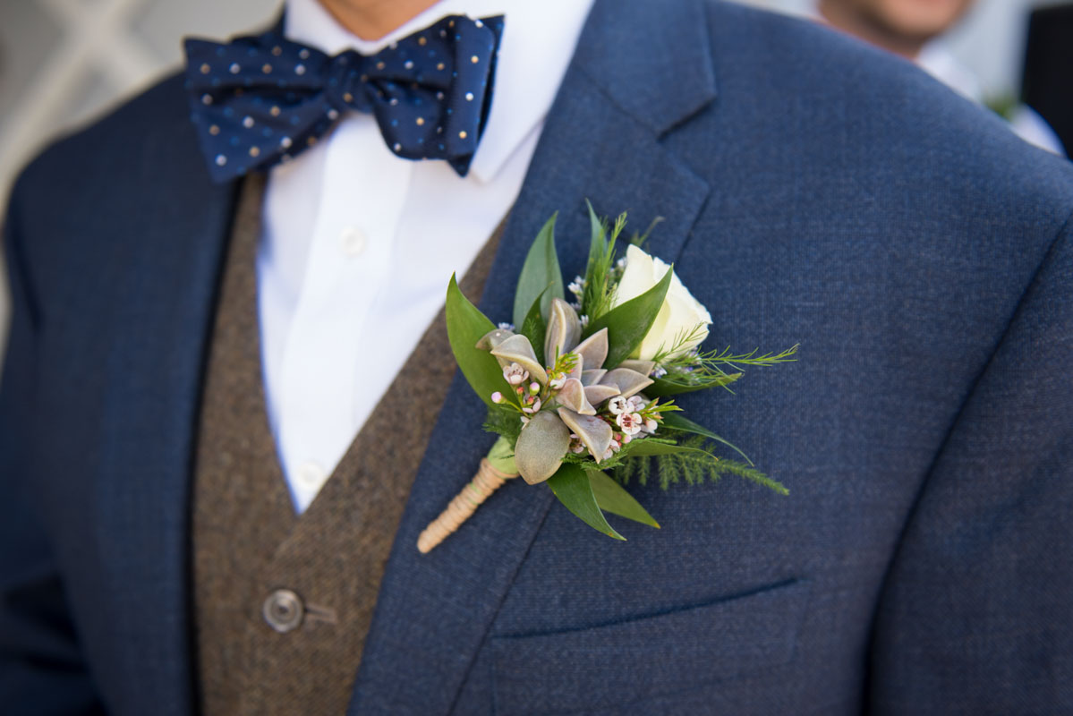 white rose and succulent boutonniere on navy suit jacket