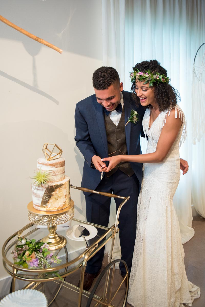 couple smiling while cutting their wedding cake