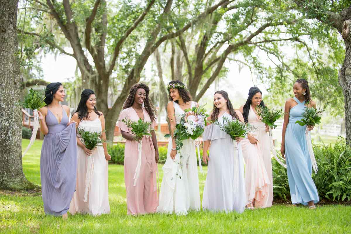 bride walking with bridesmaids in pastel gowns