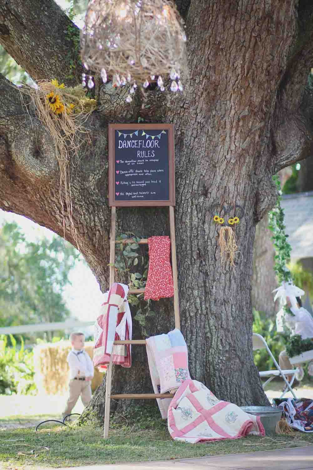 ladder with chalkboard and dance floor rules for outdoor wedding