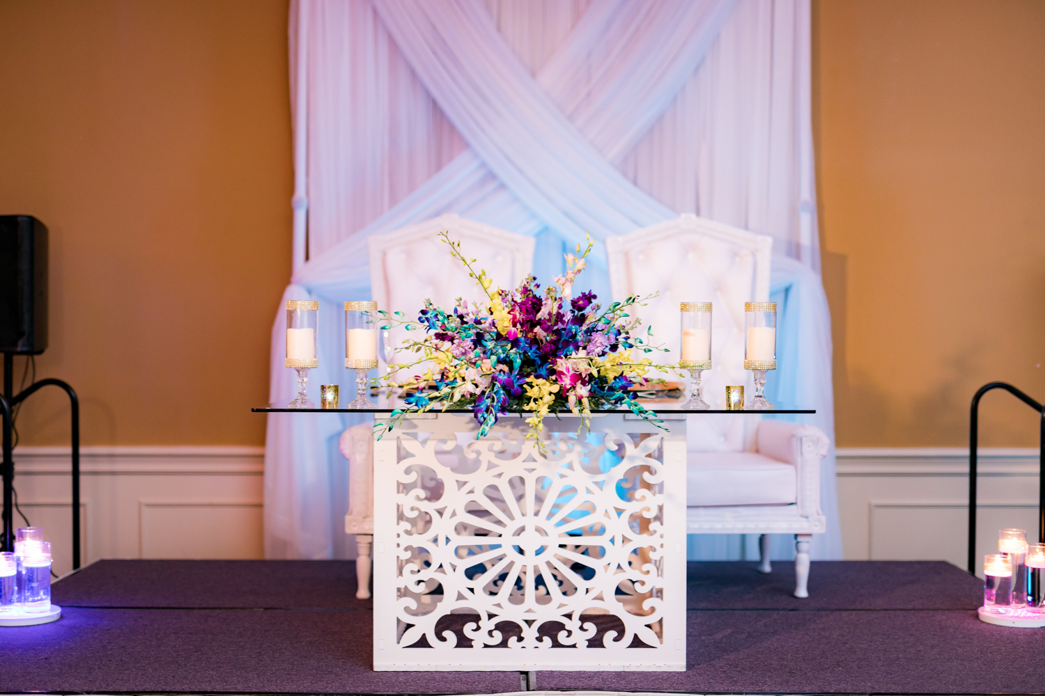 Sweetheart table with a colorful yellow, blue, and purple flower arrangement.