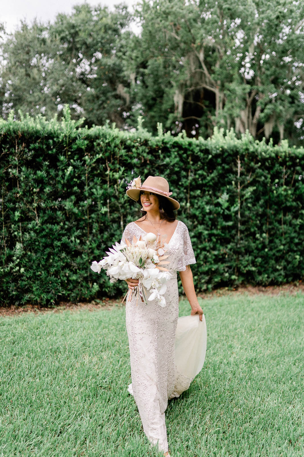 Bride holding dried floral bouquet walking in yard at the Luxmore Grande Estate