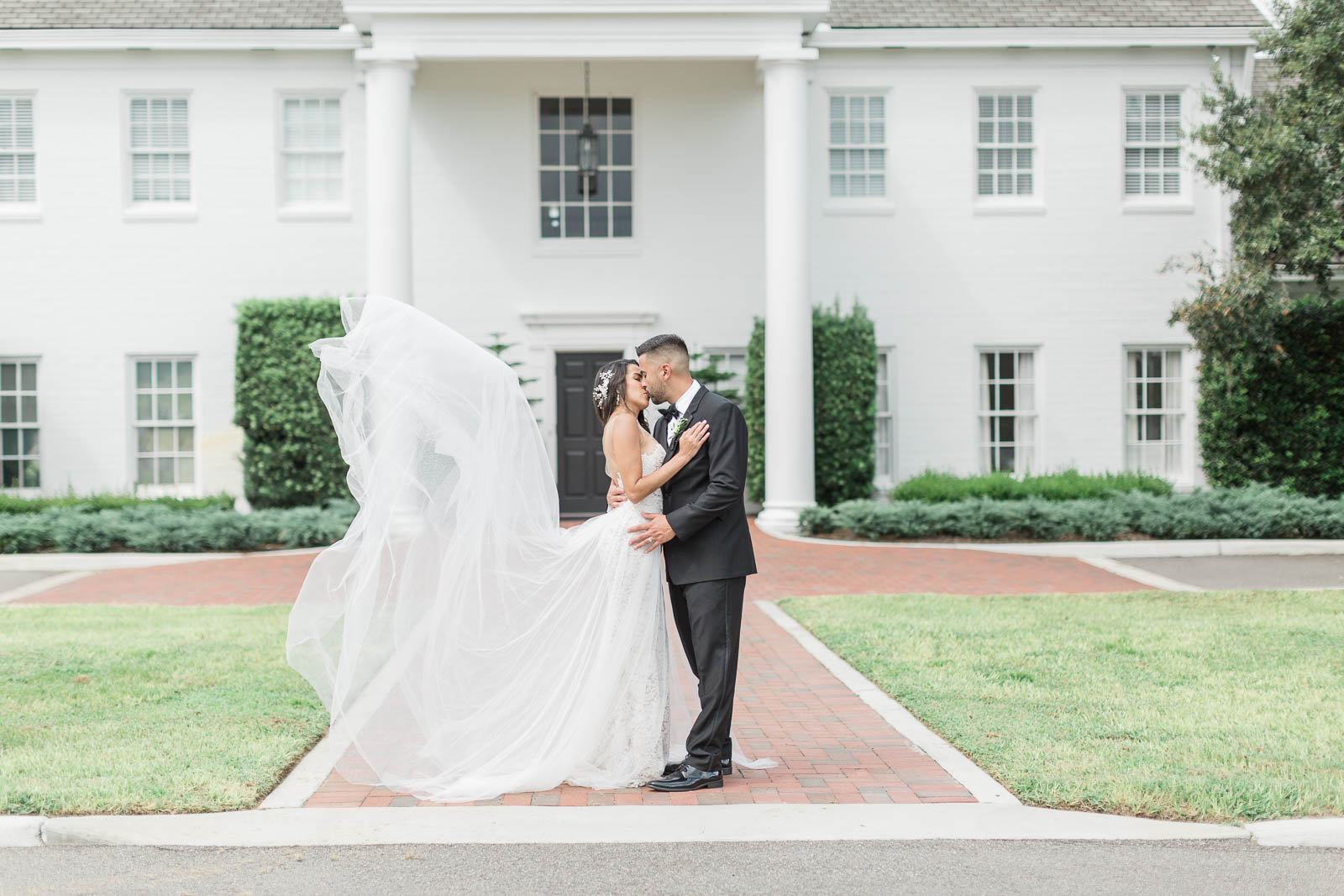 Bride and groom kissing in front of Adams Estate
