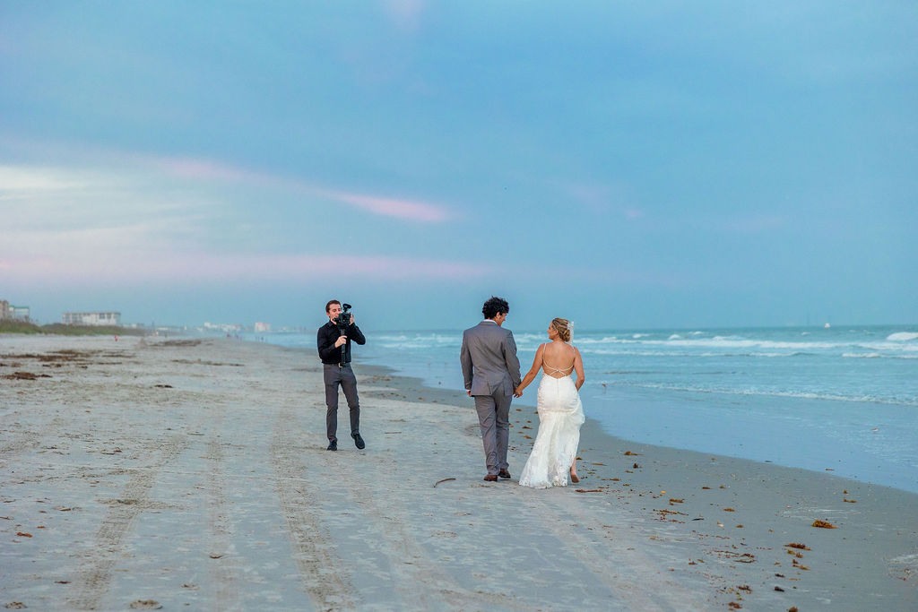 Mike DeFilippis of Jennifer Nicole Photography and Films taking video of a bride and groom on the beach